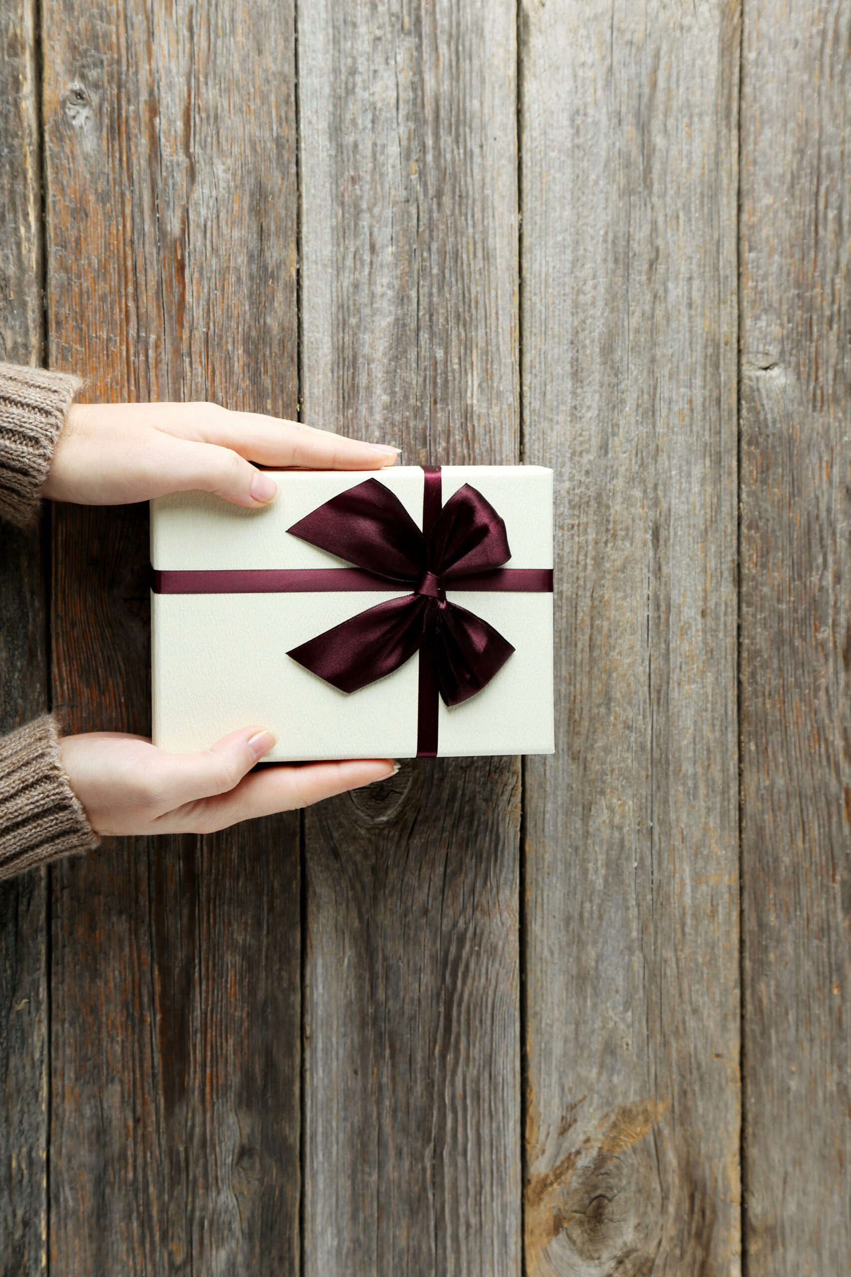 Female,Hands,Holding,Gift,Box,On,Grey,Wooden,Background